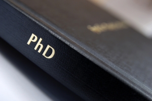 A photograph of a hard bound PhD thesis with black cover